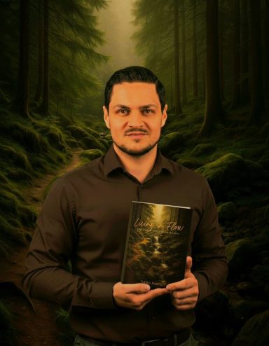 Ein Mann mit dunklem Hemd hält ein Buch in einem Wald mit moosbedecktem Boden.